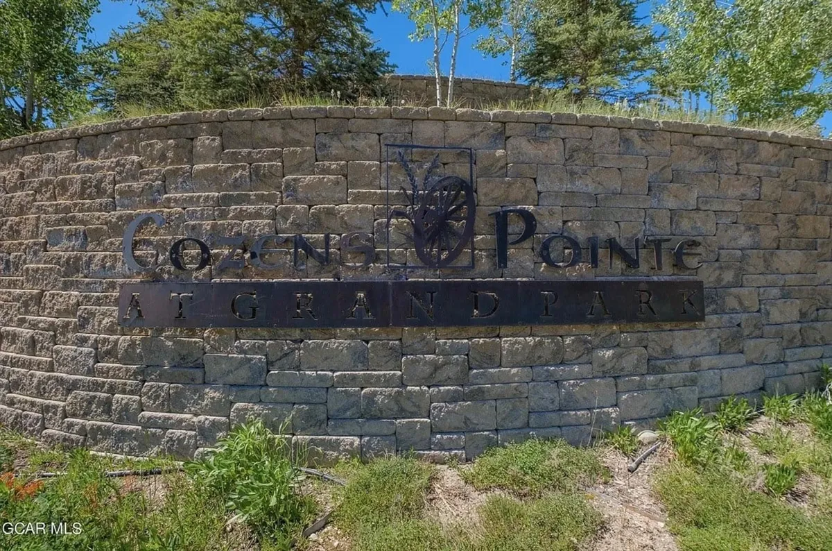 This exterior image features a welcoming stone wall and clear signage at the entry to the community, set against natural landscaping. The inviting scene hints at the broader amenities, open spaces, and the family-friendly atmosphere of the area.