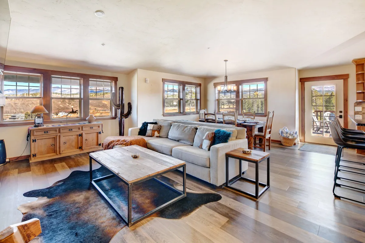 An inviting open-concept space featuring a comfortable sofa, a dining table for family meals or game nights, and large windows that frame beautiful mountain scenery. The layout fosters togetherness, making it perfect for both casual relaxation and lively gatherings.