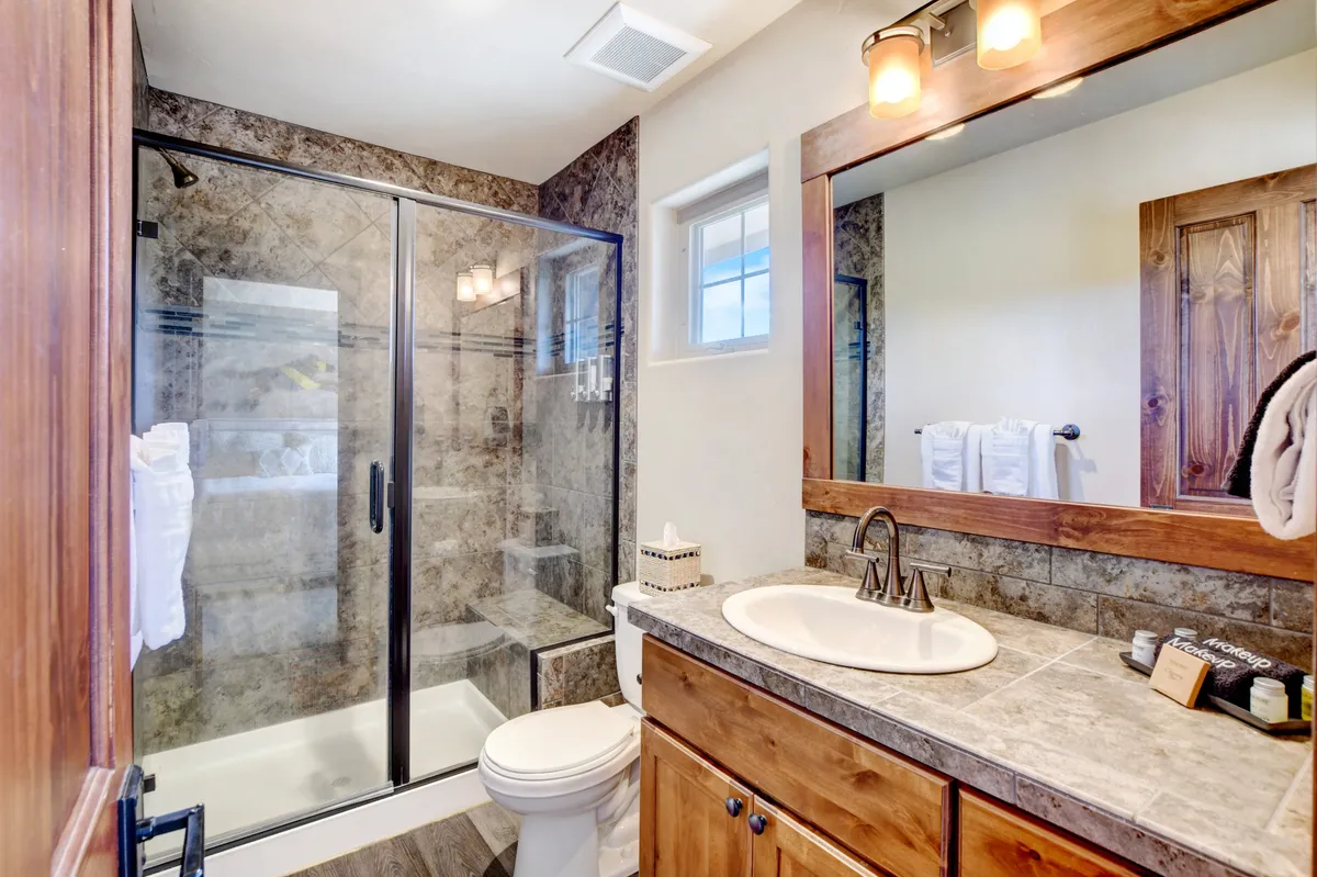 A modern bathroom with a glass shower enclosure, wooden vanity, and mirrored cabinet. The space is tranquil, inviting, and well-suited for daily routines or unwinding after a long day.