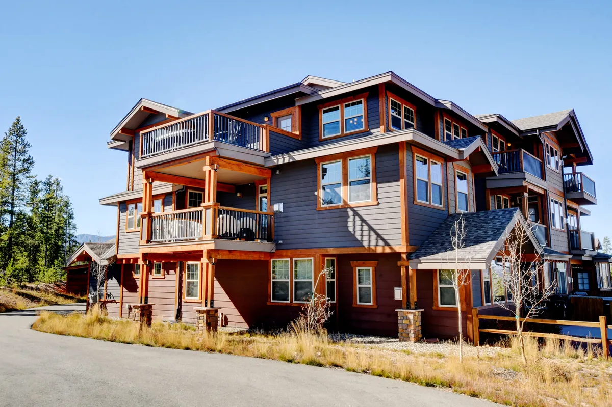 This exterior scene displays multi-level balconies with wooden siding and large windows, perfect for morning coffee or sunset views. The inviting setting hints at the social, yet peaceful, mountain lifestyle available to guests—an ideal setting for romantic or celebratory moments.